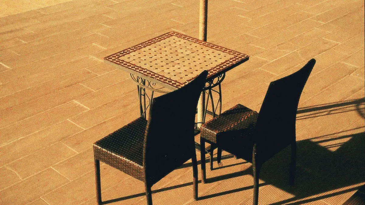 Terrasse extérieure dallée avec salon de jardin au bord d'une piscine
