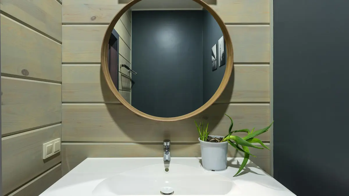 Petite salle de bain optimisée avec miroir rond et vasque compacte