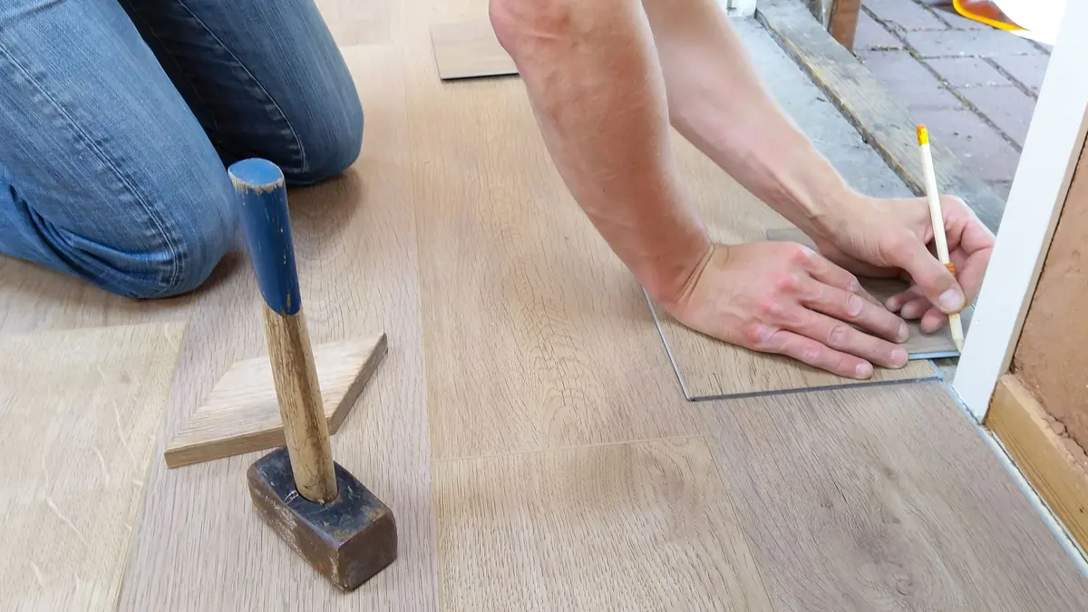 Artisan préparant et mesurant un sol avant la pose d'un revêtement